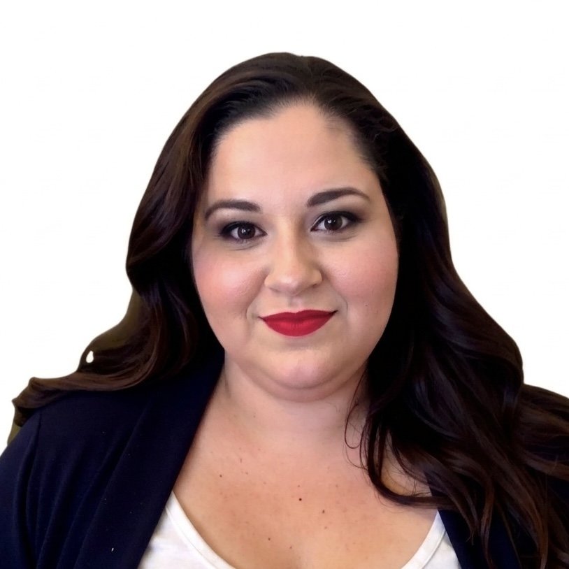Portrait of a woman with long dark hair, wearing a black blazer and red lipstick, against a white background.