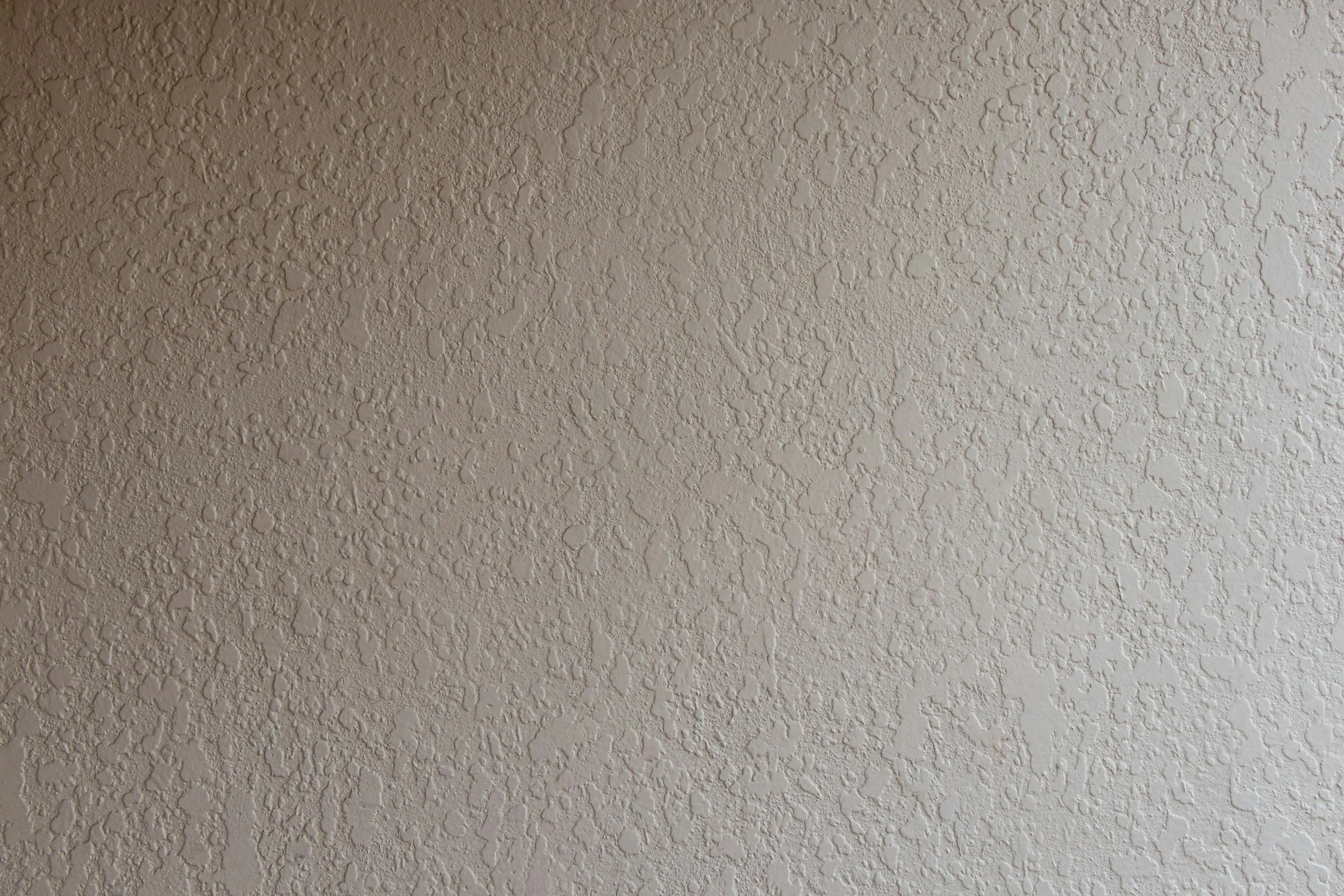 Close-up of a textured beige ceiling with small bumps and rough surface.