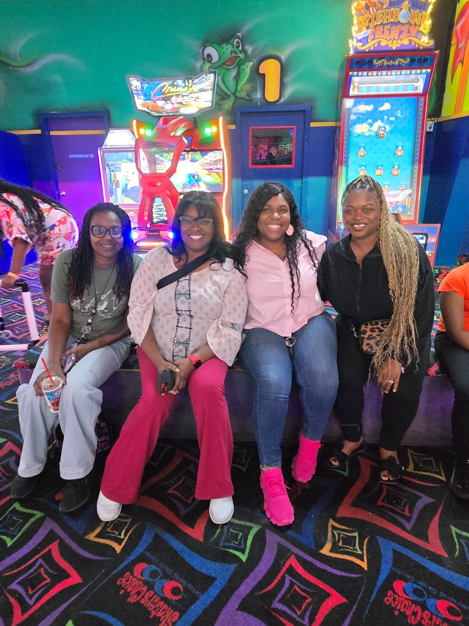 Four women smiling together during a GLOW outing at the arcade.
