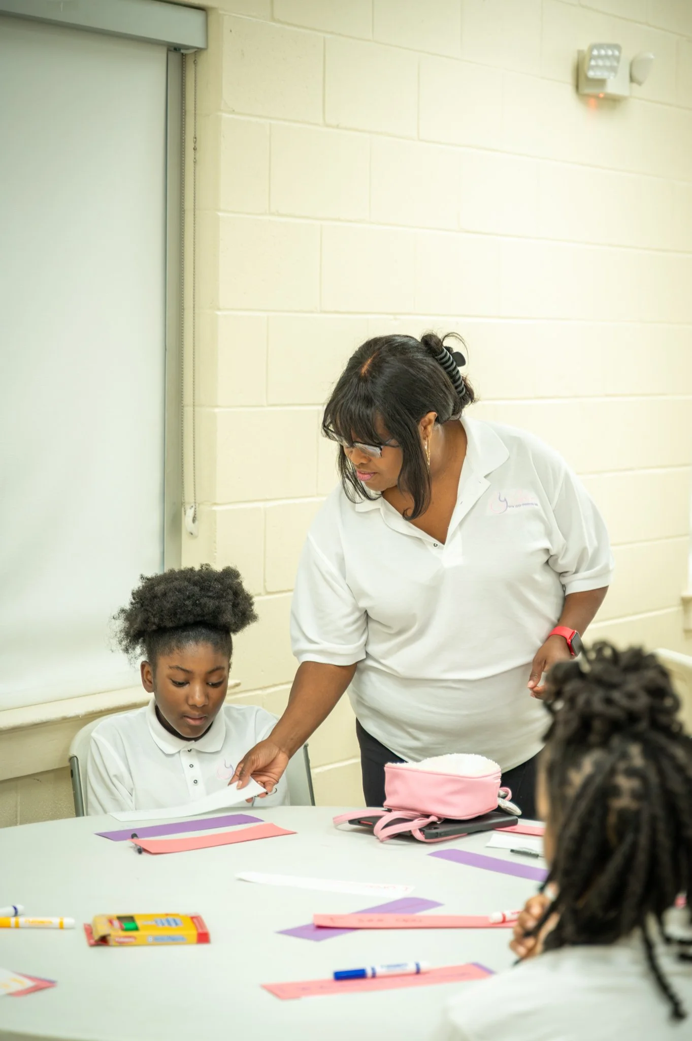 “A GLOW mentor helping a participant during a hands-on learning activity.”