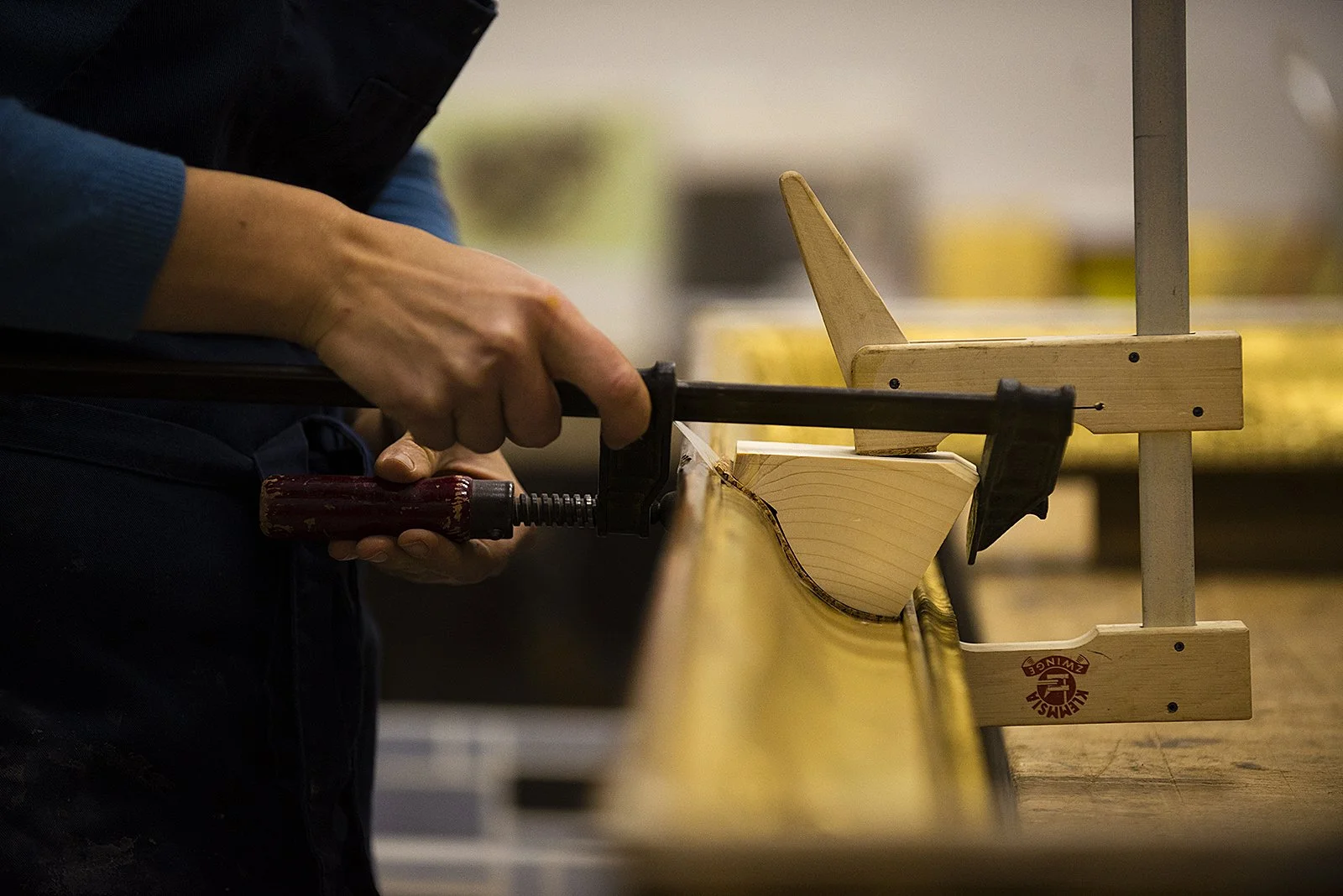 Holzarbeit, eine Person sägt ein Stück Holz mit einer Handsäge in einer Werkstatt.