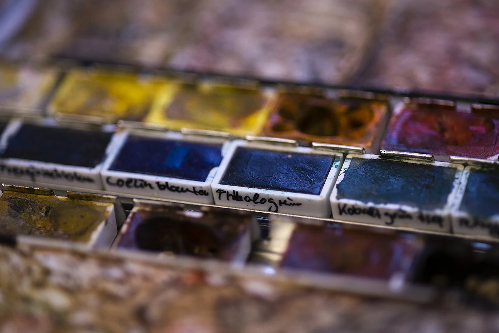 Nahaufnahme einer Wasserfarbpaintpalette mit verschiedenen Farbtönen, beschriftet mit Bezeichnungen wie "Kobalt Blau" und "Phthaloblau".