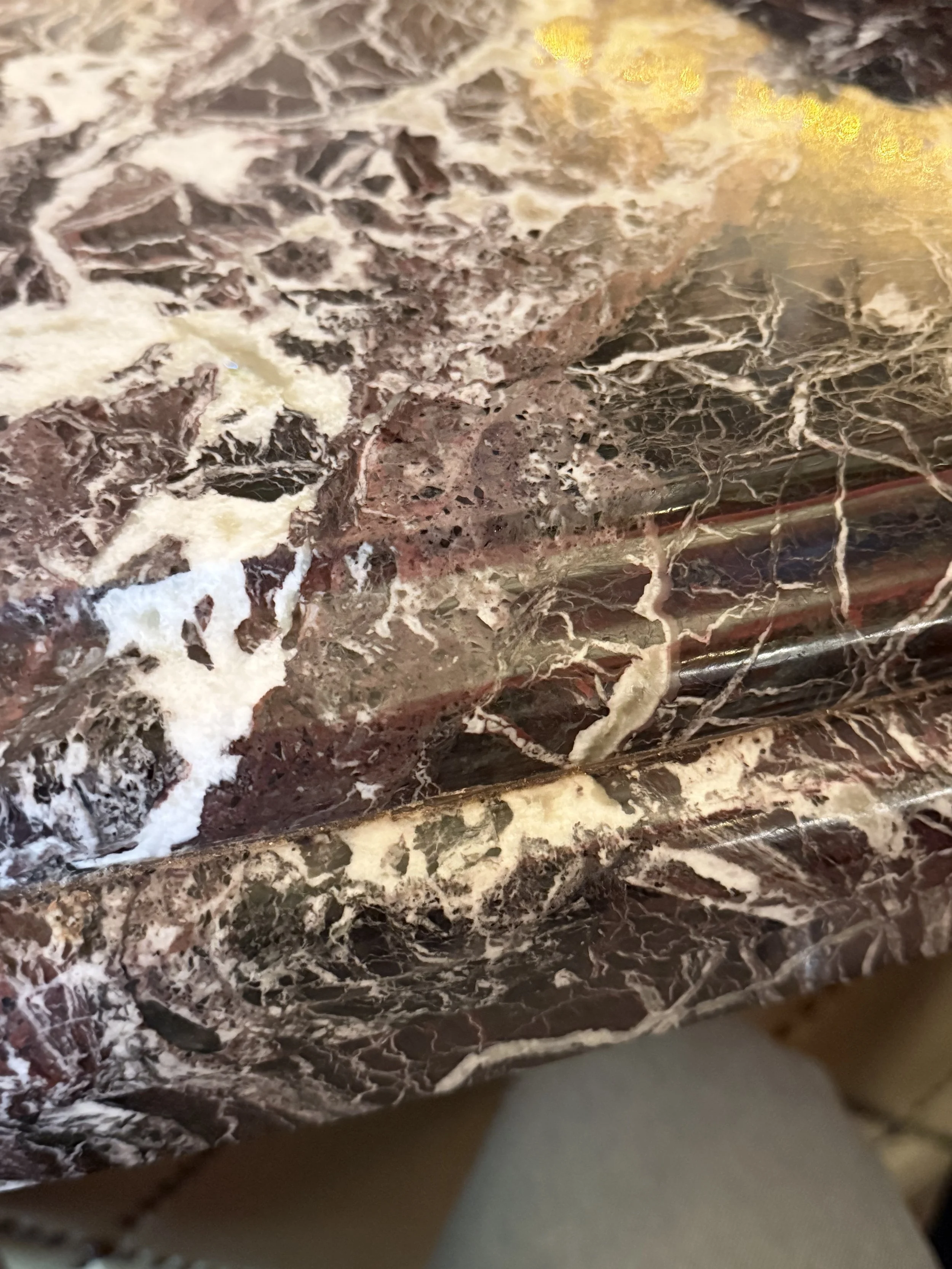 Close-up of a polished marble surface with a pattern of dark brown, white, and beige veins.