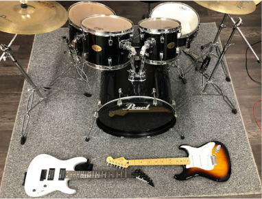 Conjunto de batería y dos guitarras eléctricas en un escenario.