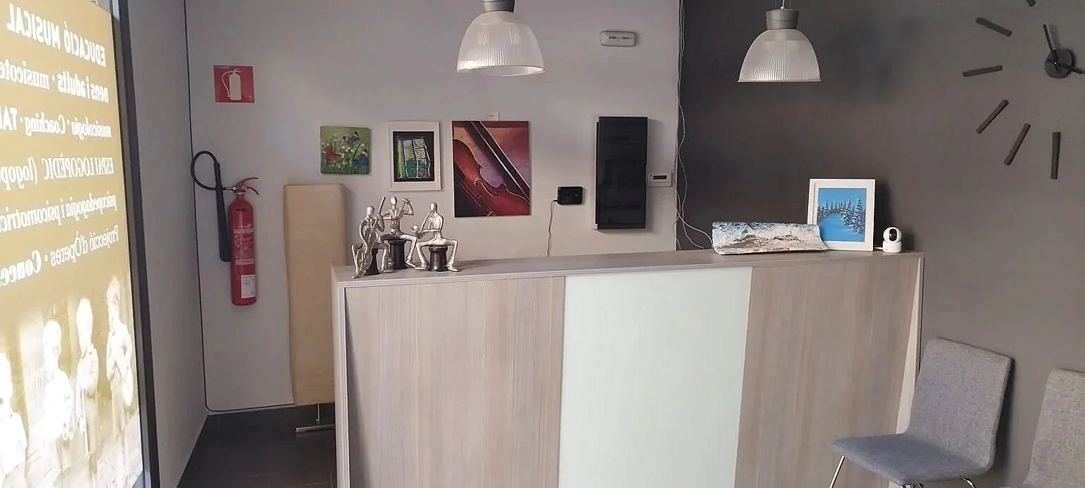 Recepció de l'Espai Musical de Terrassa amb decoracions, un rellotge a la paret grisa i objectes sobre el mostrador.