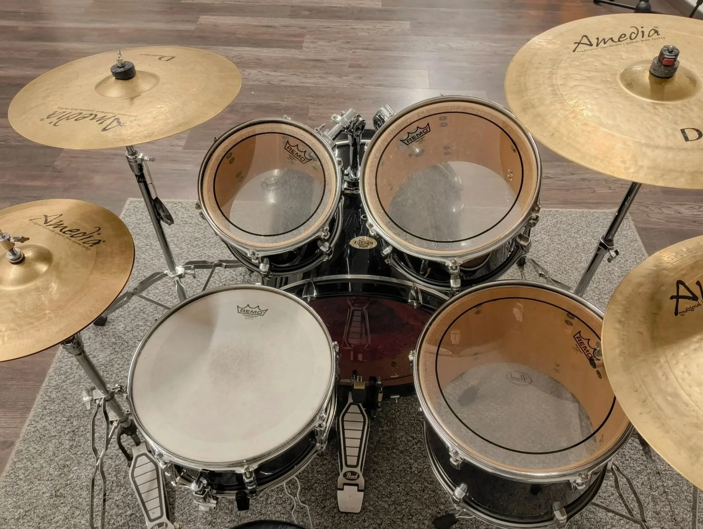 Batería de batería de batería, con platillos y timbales, en un piso de madera y alfombra