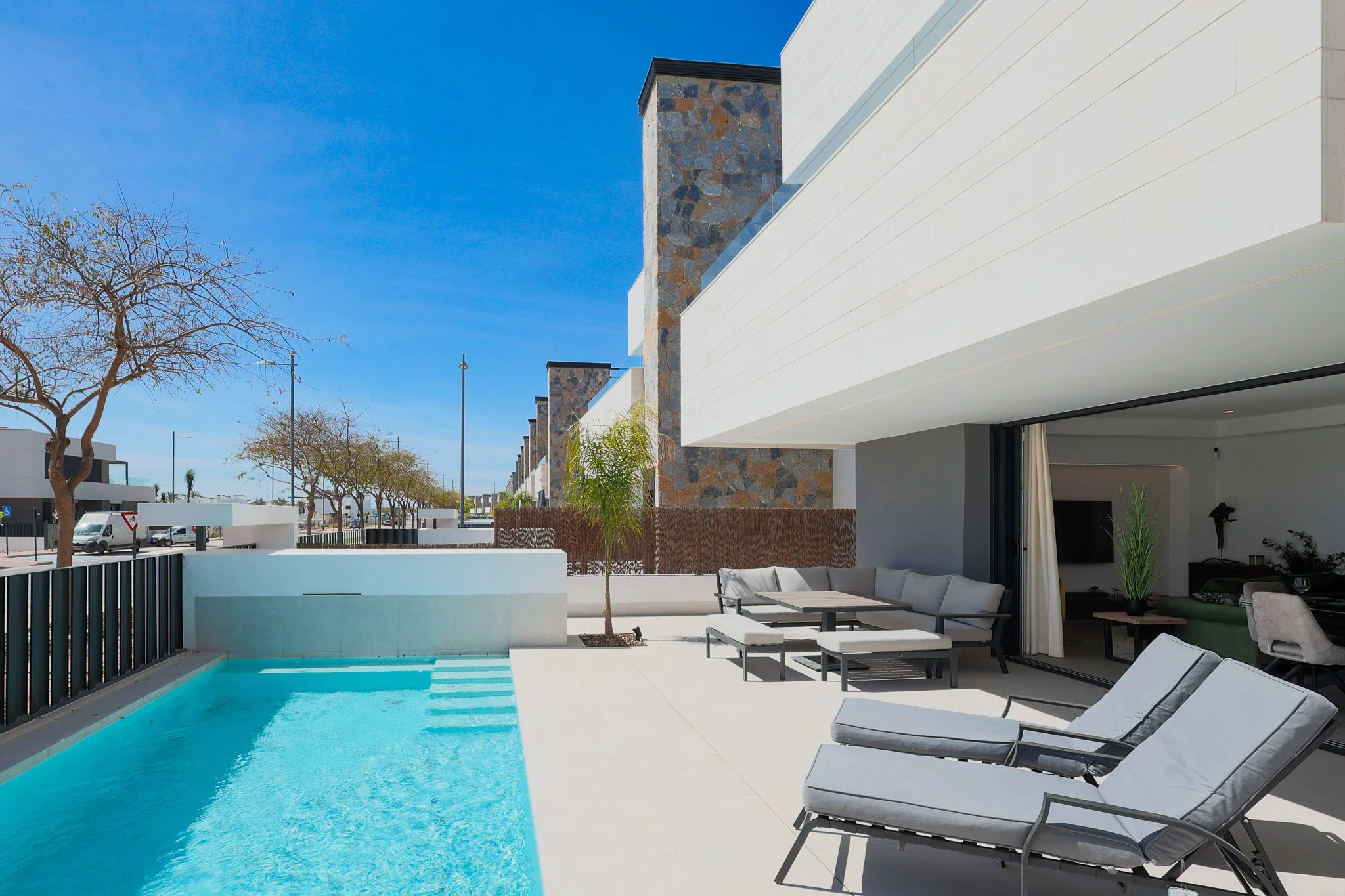 Modern Holiday home backyard with a swimming pool, seating area with lounge chairs, and a house with large open windows under a clear blue sky. on Santa Rosalia Lake Resort