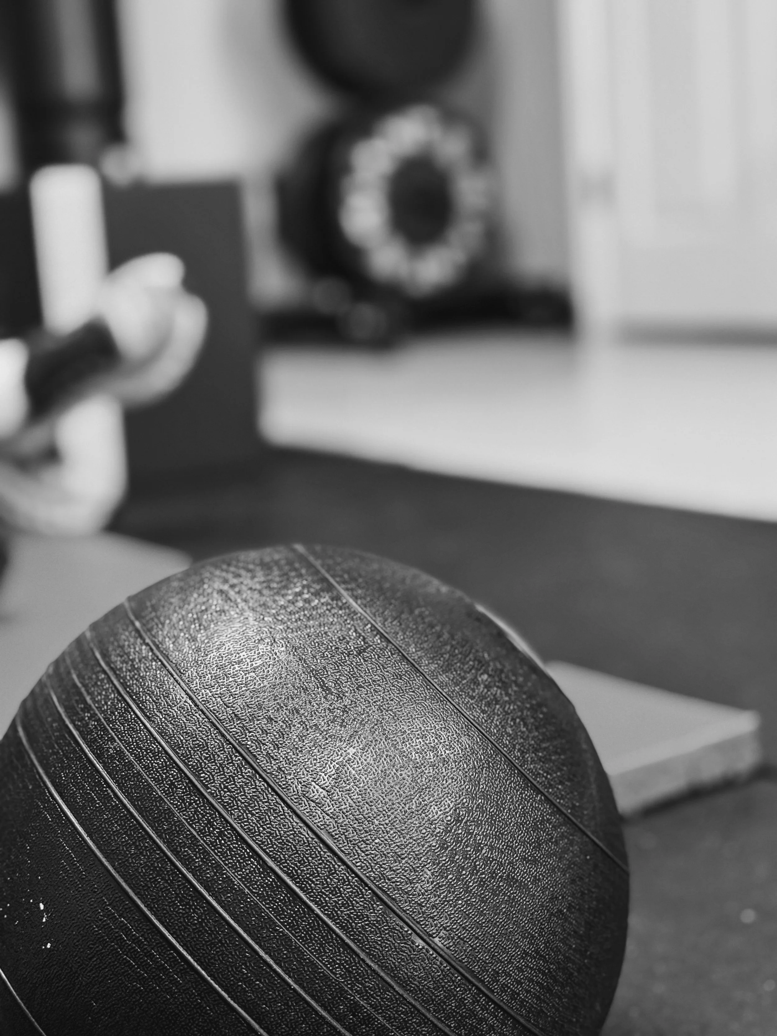 Close-up view of a med ball with textured surface and grooves, positioned on a flat surface in the foreground.