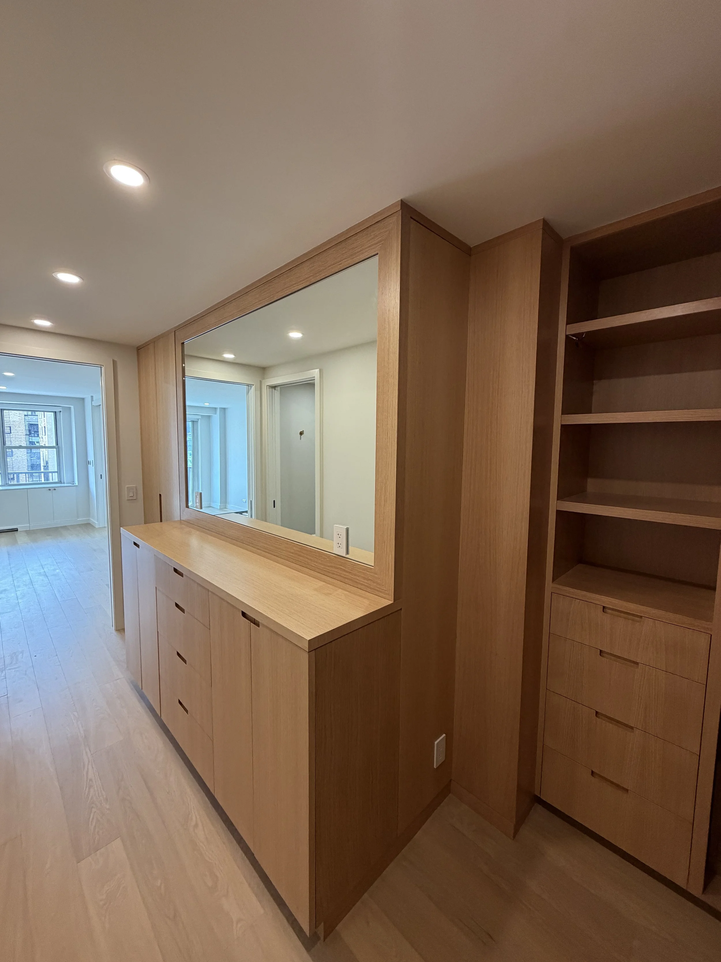 Interior of a modern home with light wood cabinets, built-in shelving, and large windows that let in natural light.