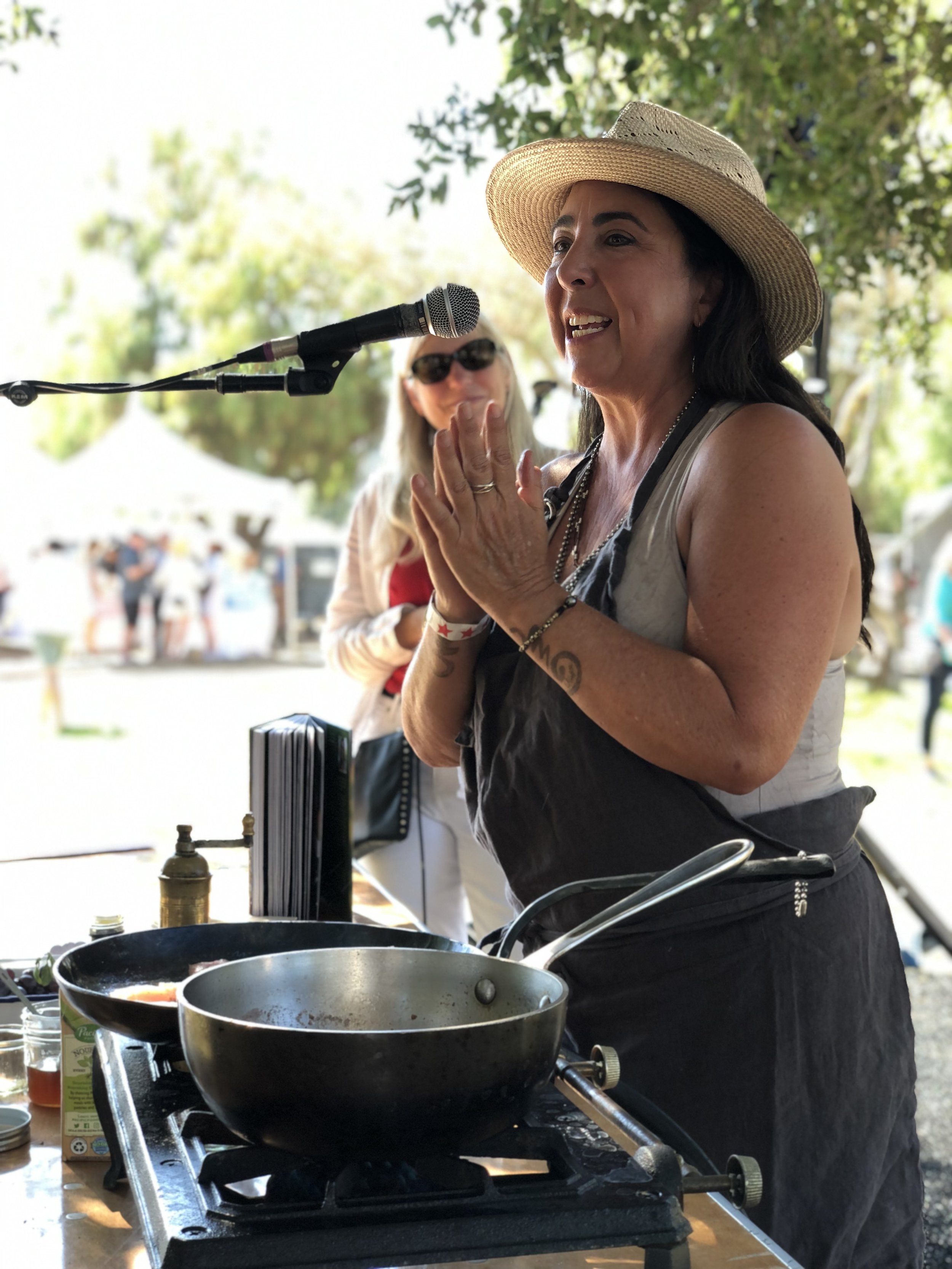 Chef Robin cooking on a stovetop at an outdoor cooking demo event.