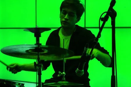 Photograph of Adam Wilkie playing a drum kit while working as a session drummer in the early 2000s