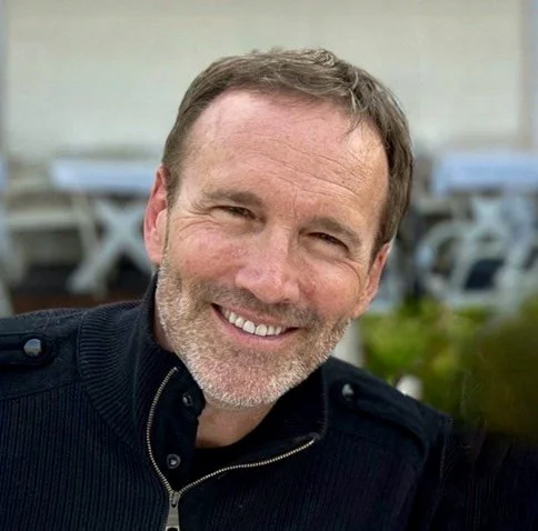 Breton Buckley, CEO of Breton Buckley Marketing LLC, a smiling middle-aged man with short brown hair, a beard, wearing a black zip-up jacket, outdoors.