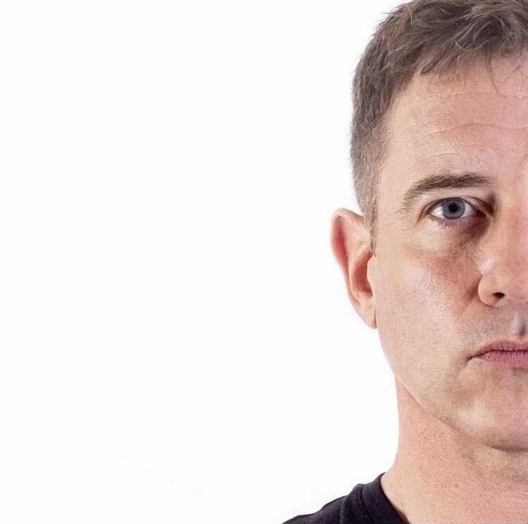 Half of a man's face against a white background, focusing on eyes and expression.