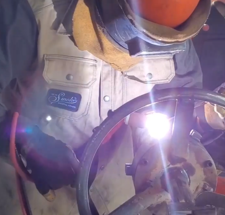 A person tig welding a cap on carbon steel pipe.