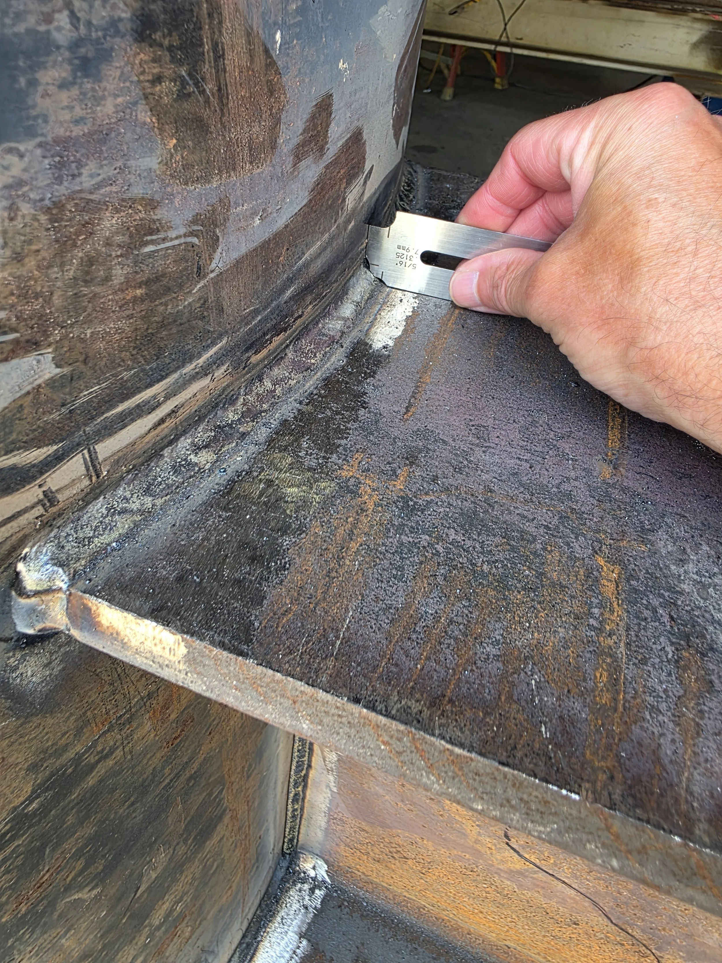 Welding inspector measuring a fillet weld with a fillet weld gauge.