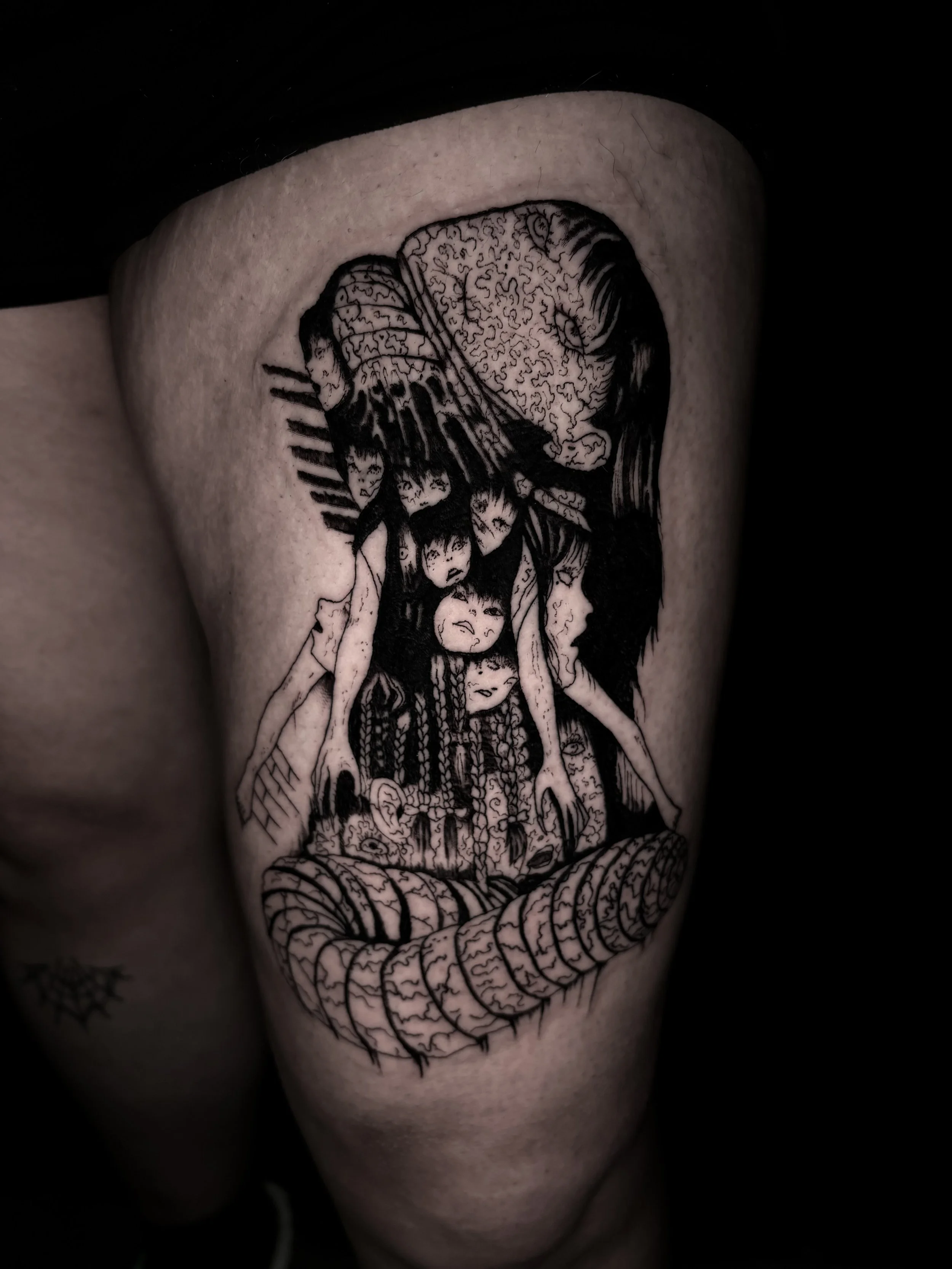 Black and white tattoo of a woman with her eyes closed, smiling with her head resting on her hand, and surrounded by intricate patterns and faces.