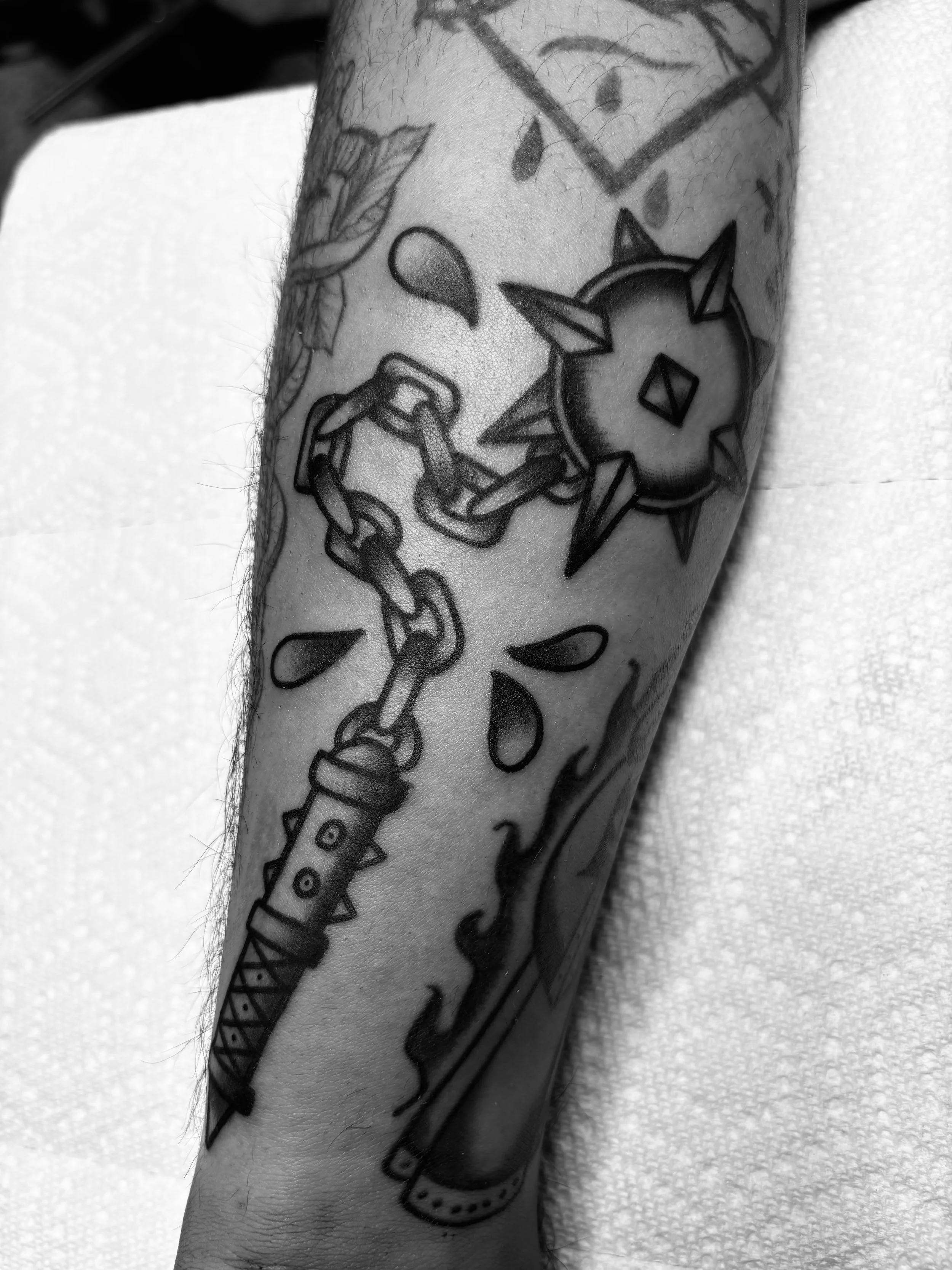 Black and gray tattoo of a dragonfly and a star-shaped object on a person's forearm.