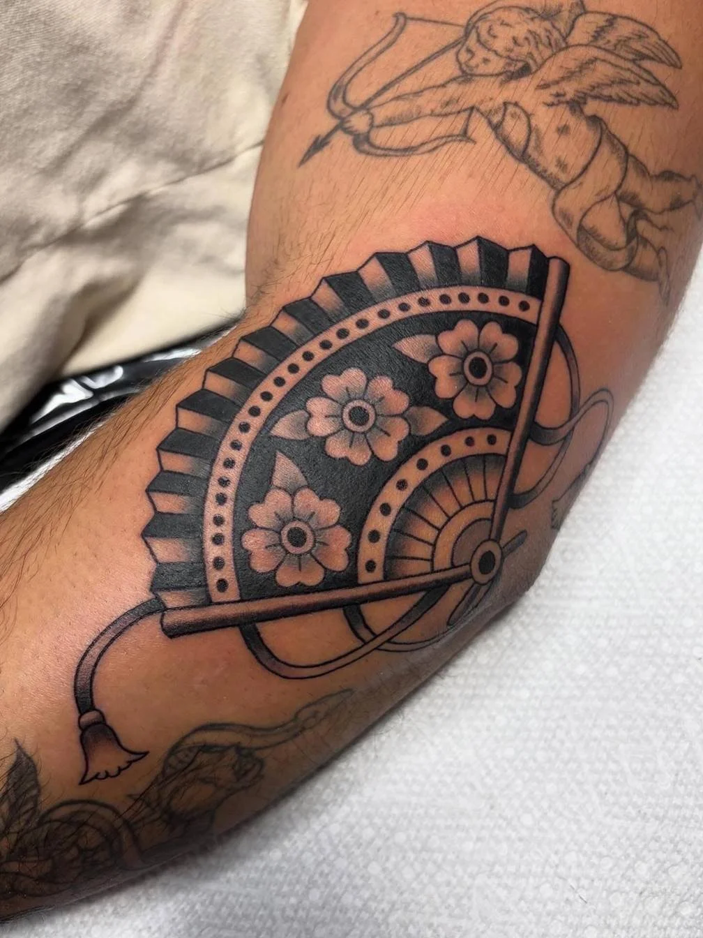 Tattoo of a semi-circular floral design with decorative elements on a person's arm.