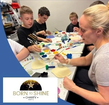 Children and an adult working on arts and crafts projects at a table with paints and clay, with a 'Born to Shine' charity logo in the corner.