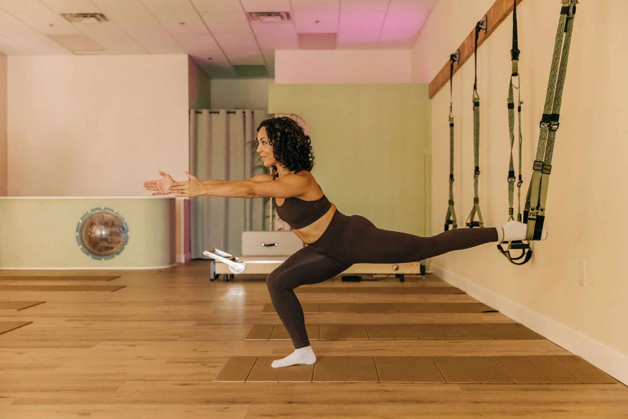 Coach Ren performing a Pilates Suspension Method pose on the TRX at Fortuna Fitness studio.
