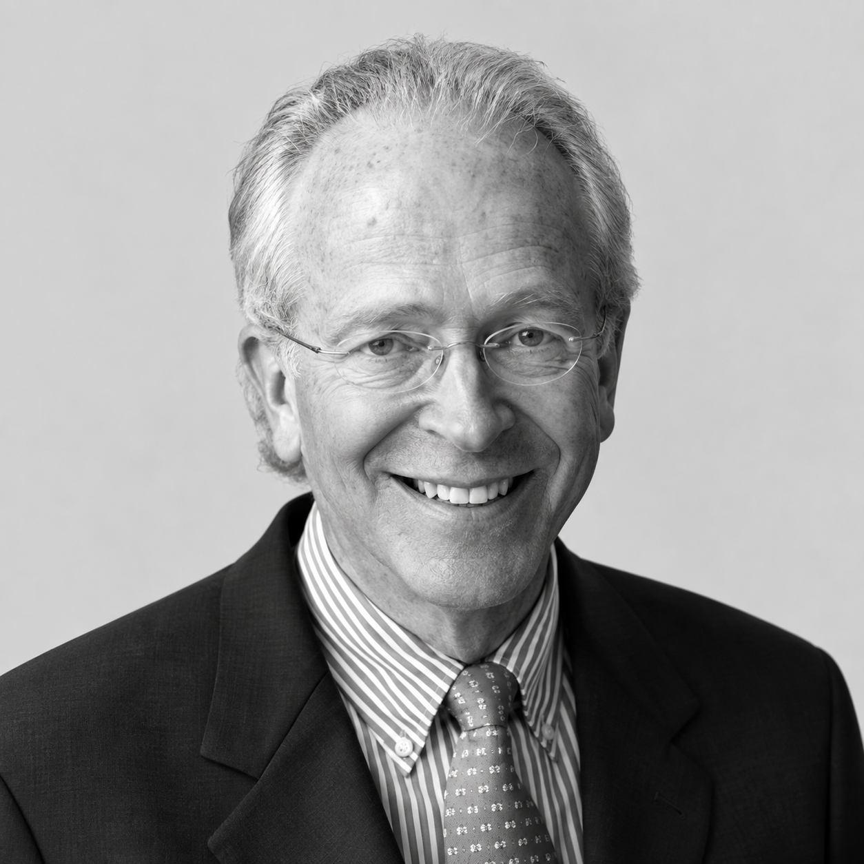 Robert Elde - Black and white portrait of an older man with glasses, gray hair, wearing a suit, striped shirt, and patterned tie, smiling.
