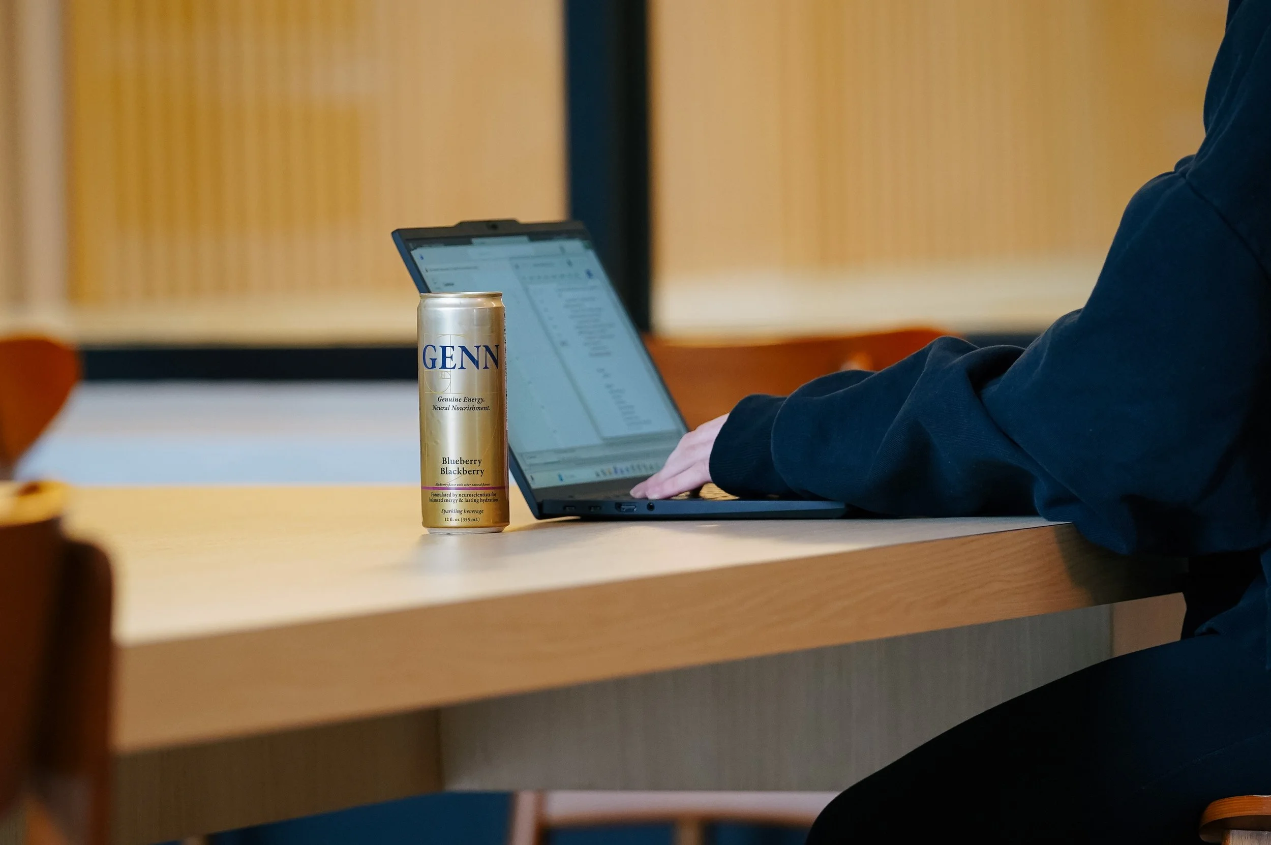 GENN Energy beverage beside a laptop at a workspace.