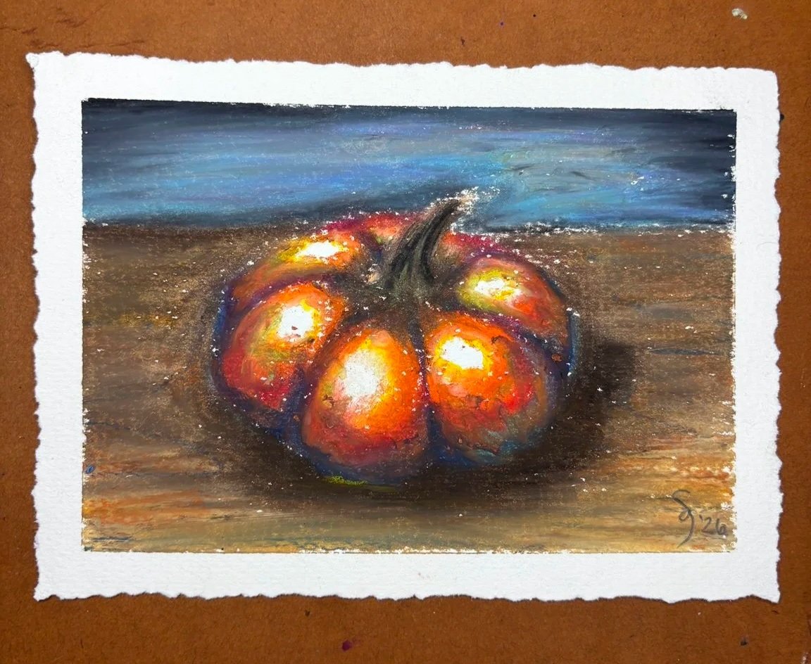 Orange pumpkin with a curling stem on a brown tabletop and blue background, drawn in oil pastel on handmade deckled paper.