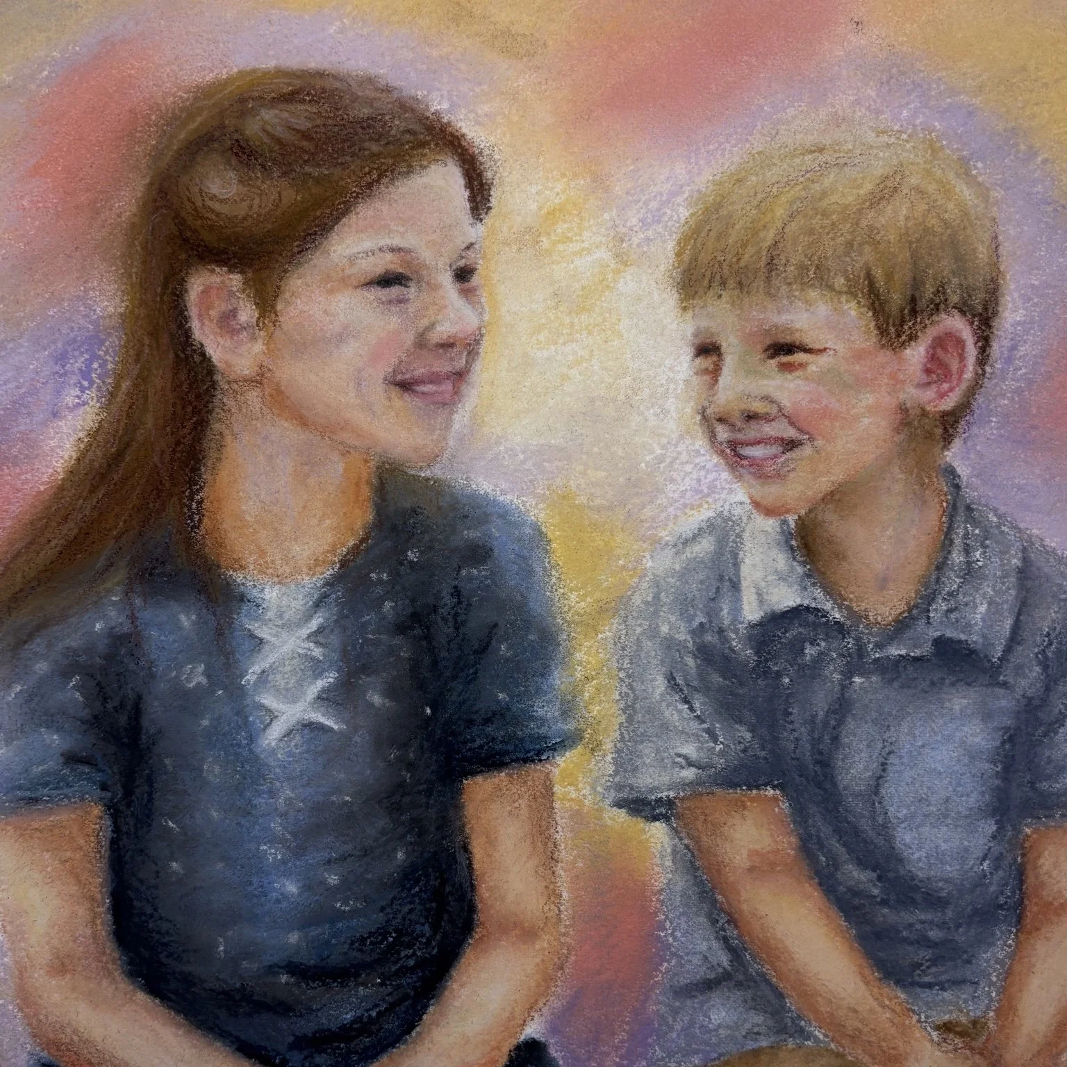 A woman and a young boy smiling at each other against a colorful background.
