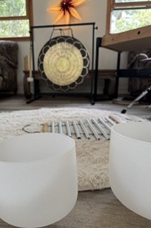 Room with a musical gong, two white bowls, a rug, and a cozy space with natural light