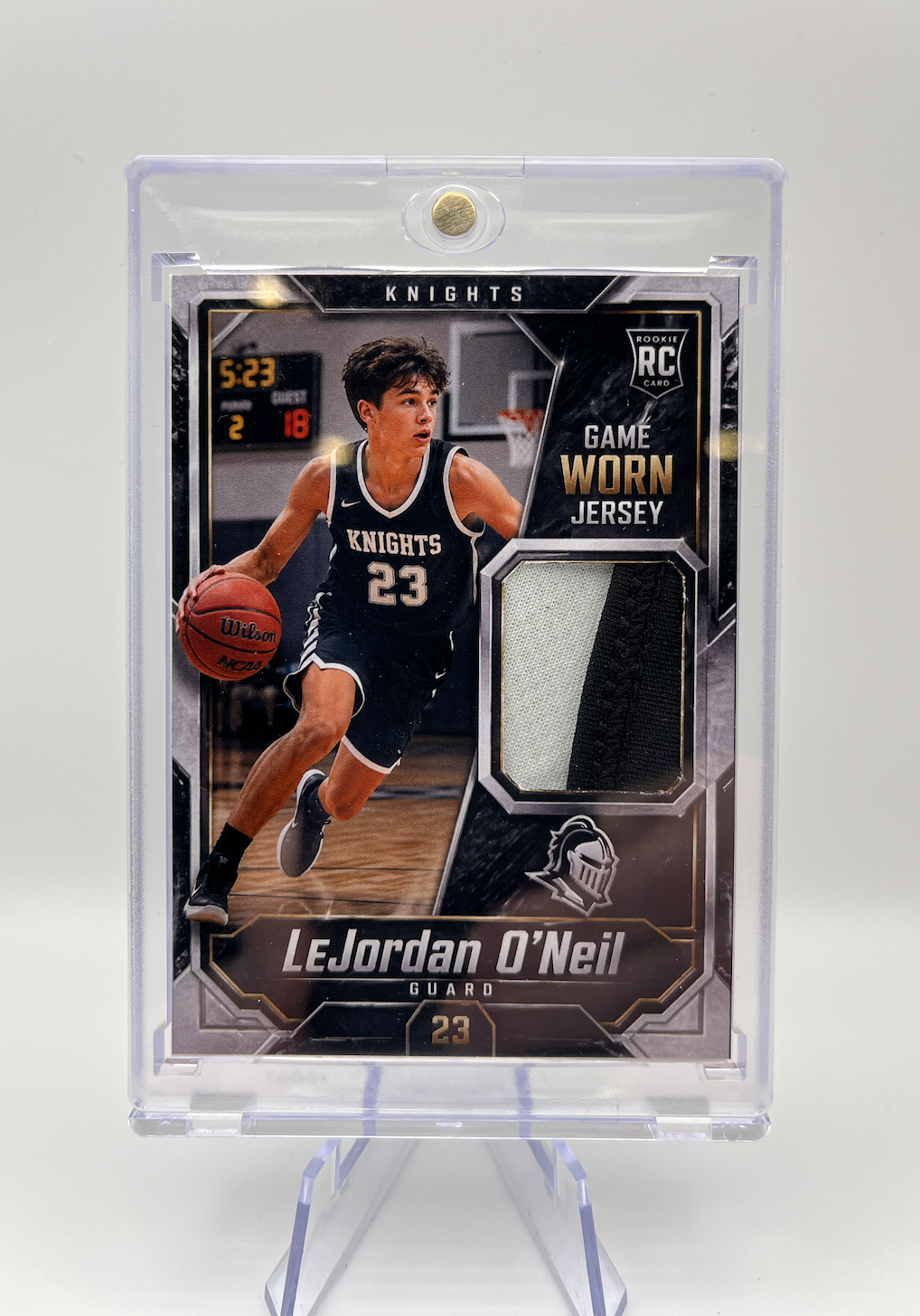 Basketball trading card of LeJordan O'Neil, a basketball player wearing a black and white jersey with the number 23, dribbling a basketball on a court.