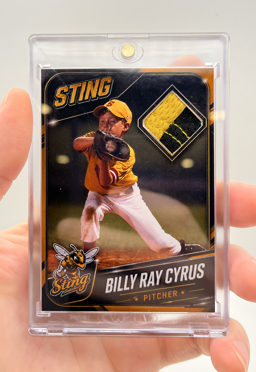 Baseball trading card of Billy Ray Cyrus as a pitcher for the Sting team, featuring an action shot of a young boy in yellow and white uniform with a glove and baseball cap, and a fabric swatch patch in the top right corner.