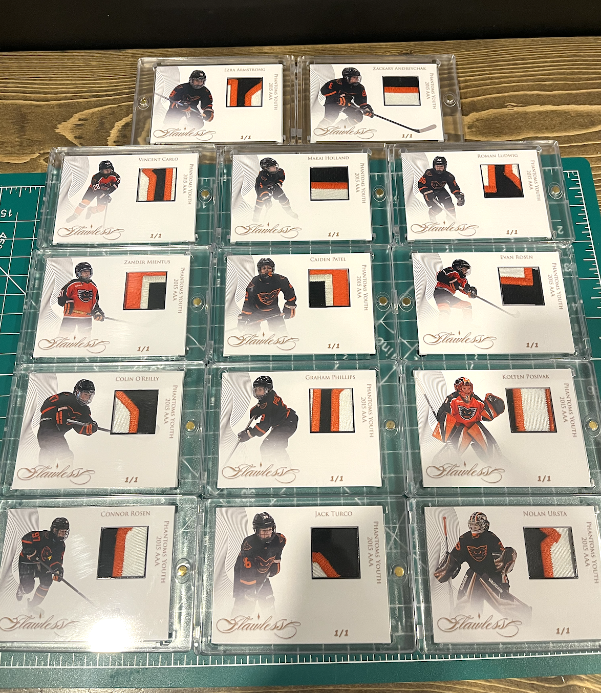 Collection of hockey trading cards featuring players in black and orange uniforms, each with a piece of fabric attached, displayed in plastic cases.