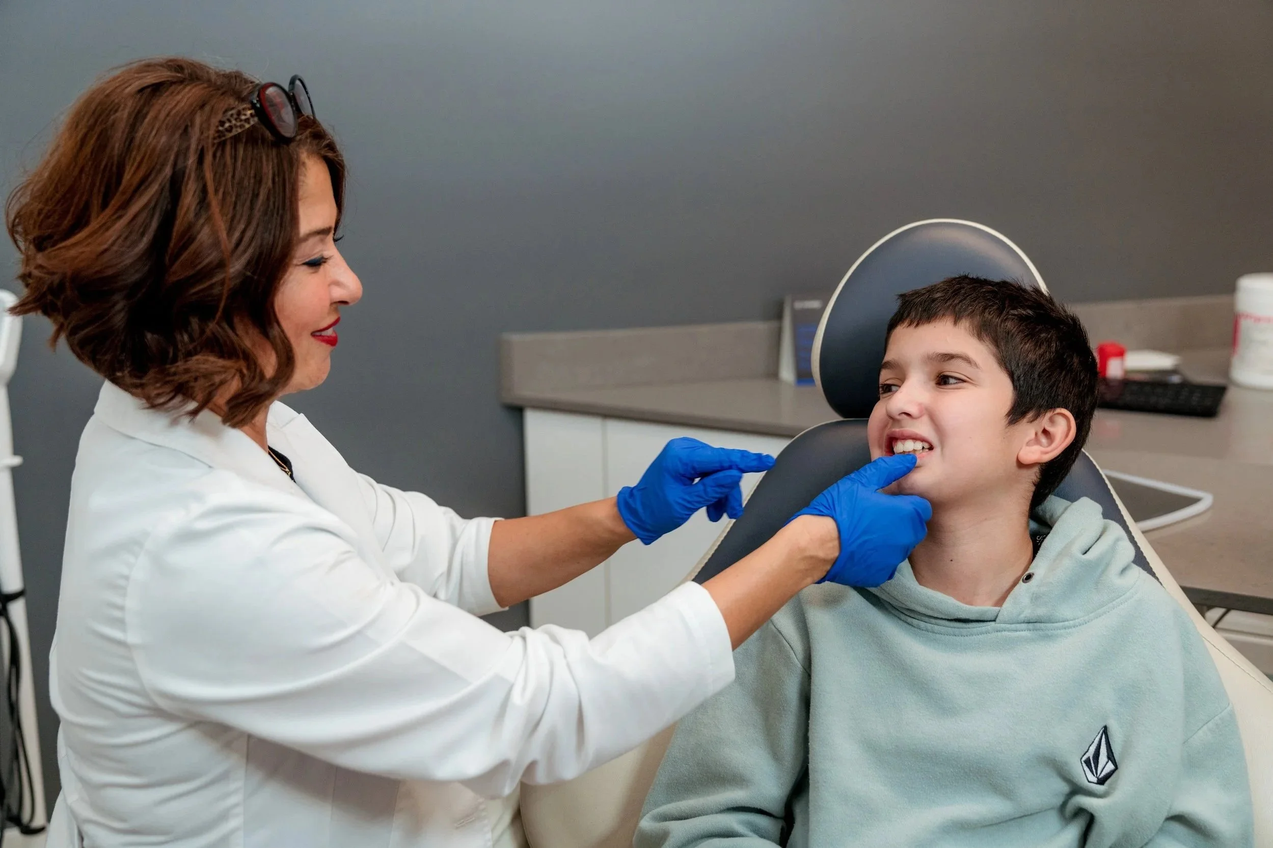 Dr. Kathy Shafagh checking a young patient’s teeth in the treatment chair at Ortho Planet.