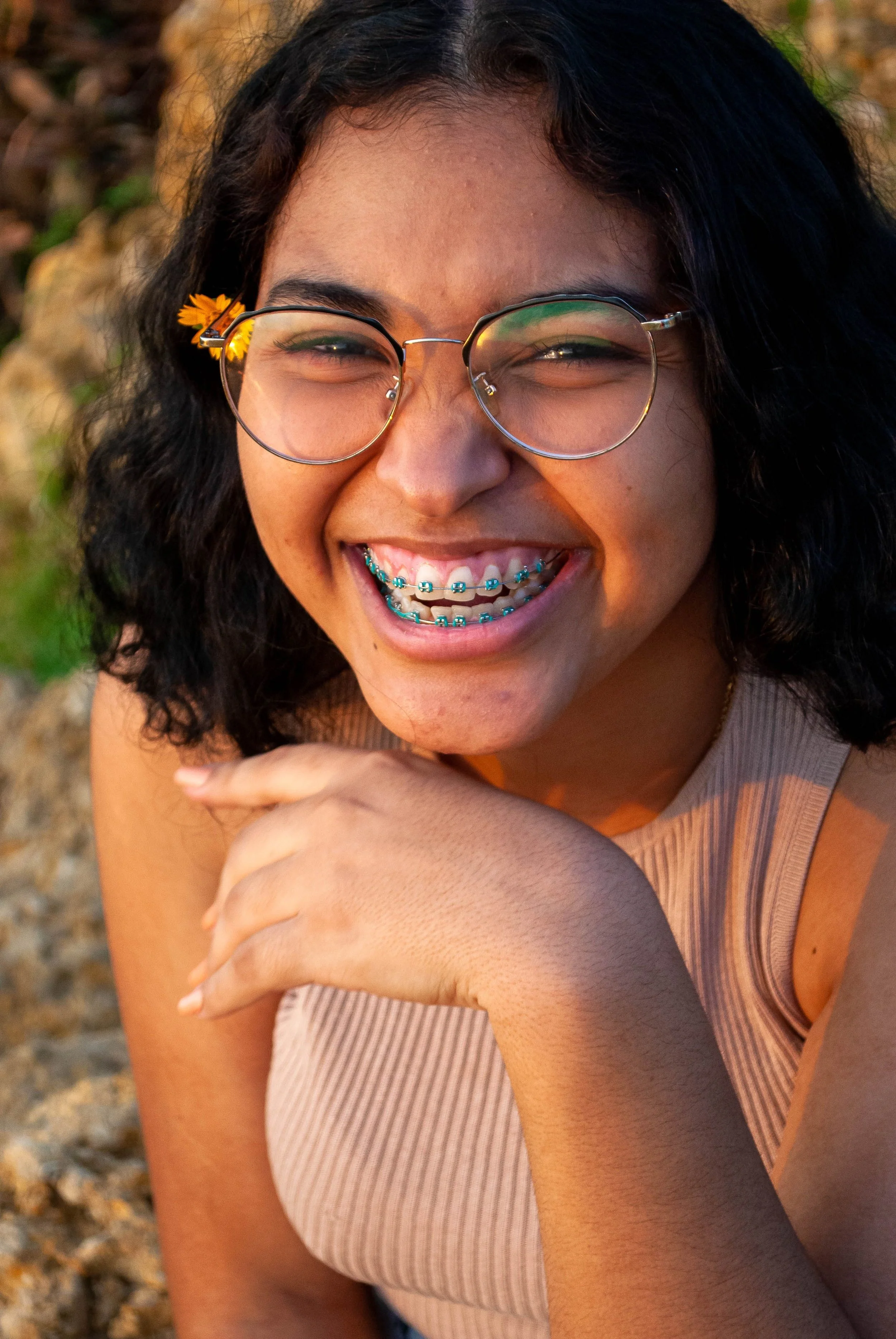 Teenage girl with glasses smiling with metal braces.