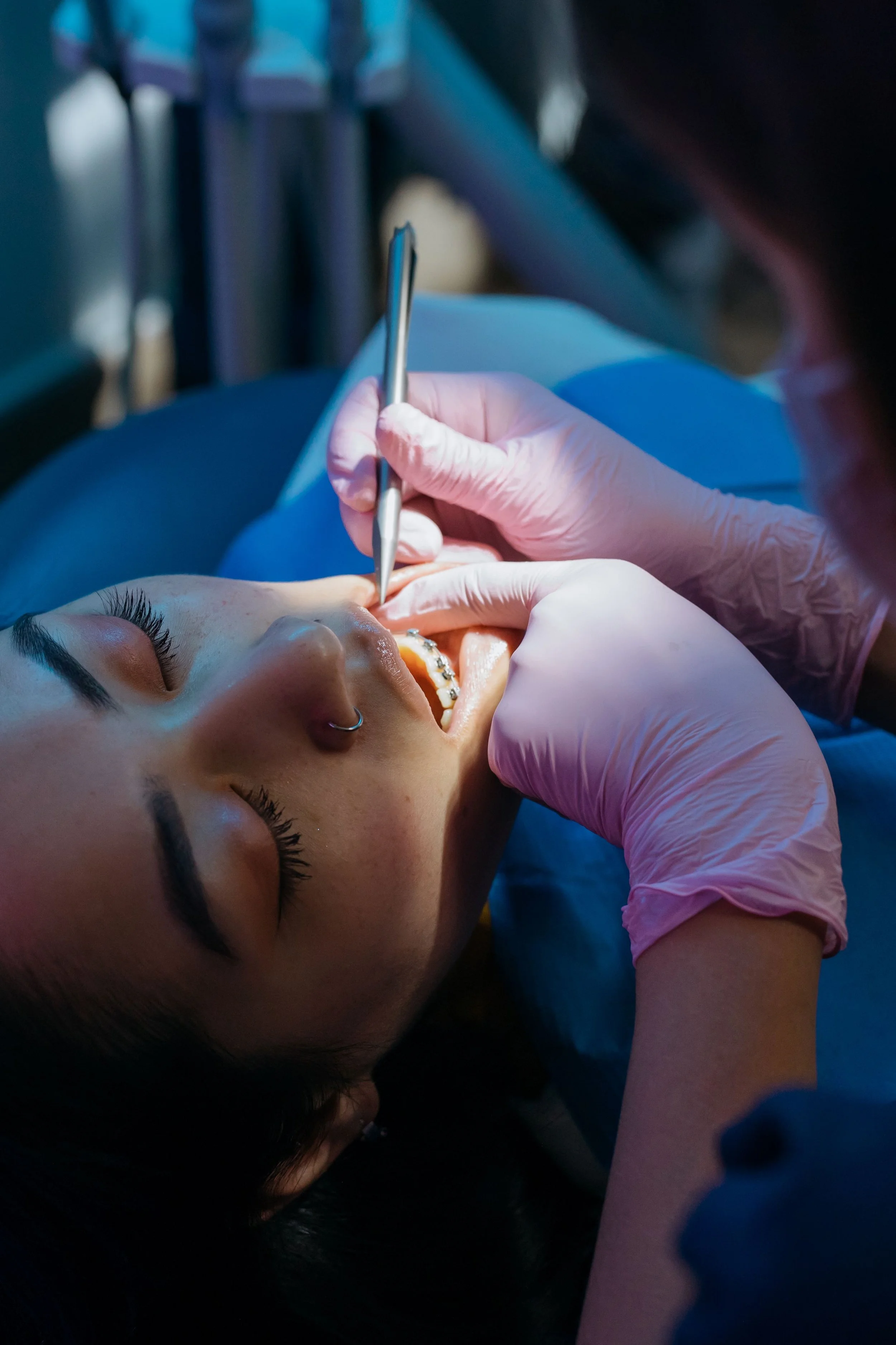 Orthodontist adjusting a patient’s metal braces during an appointment.
