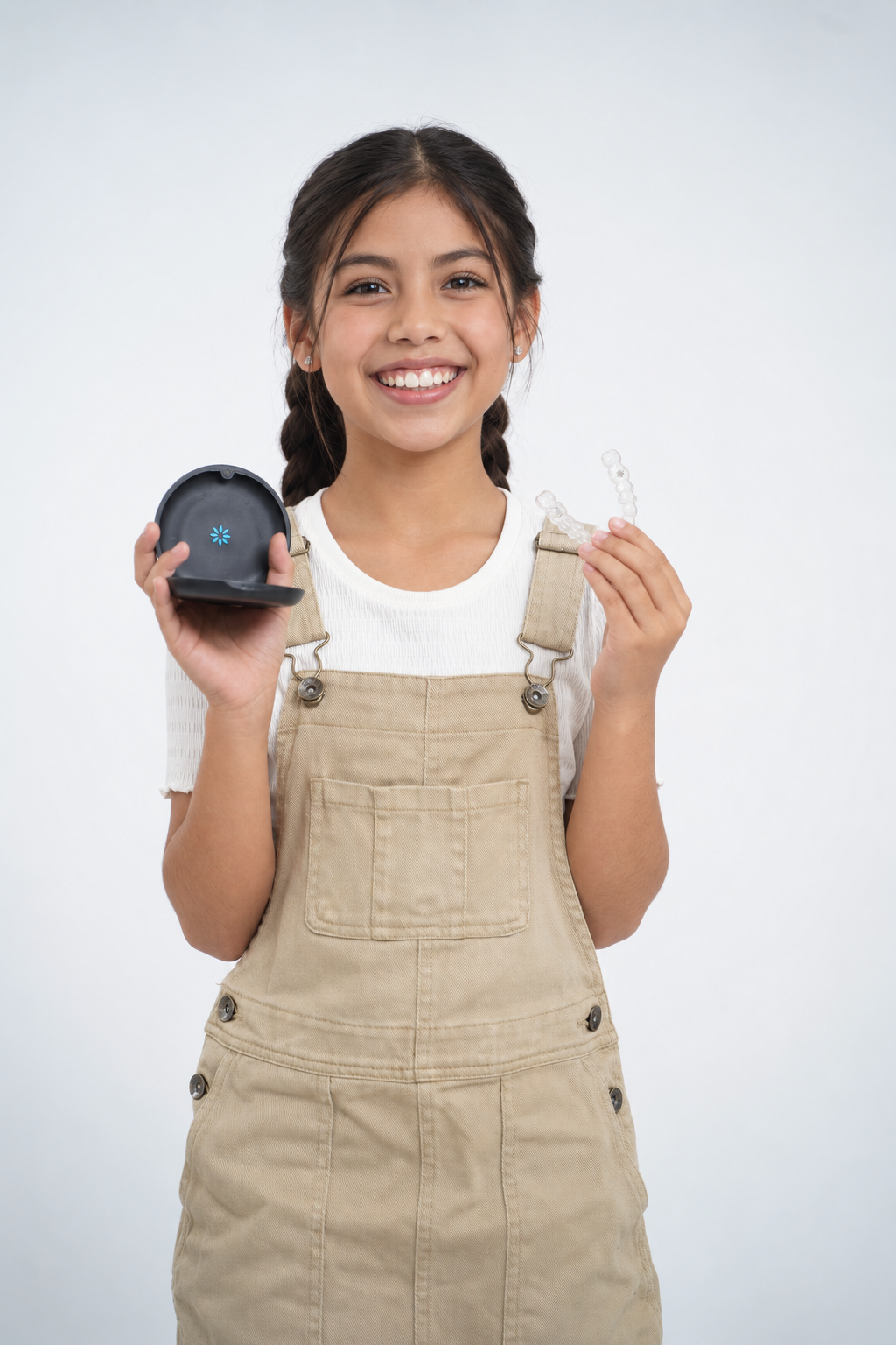 Young girl smiling while holding a clear aligner and its carrying case.