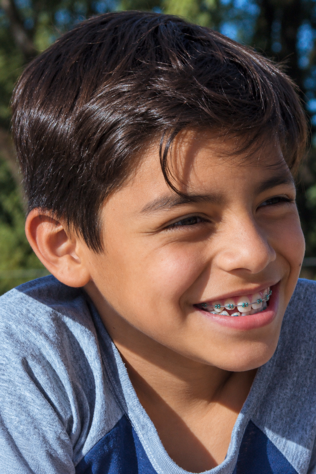 Boy smiling outdoors with metal braces.
