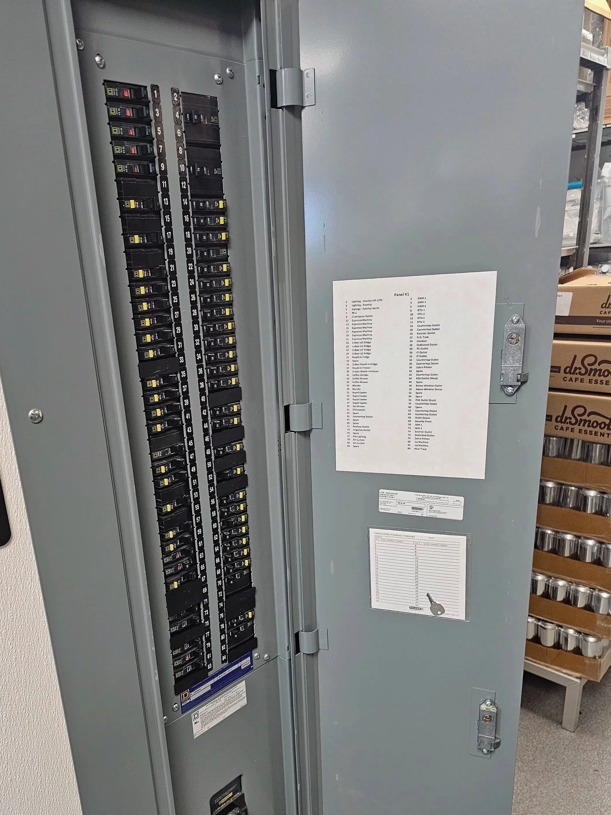 Electrical circuit breaker panel with labeled switches and a printed schedule attached to the inside of the door.