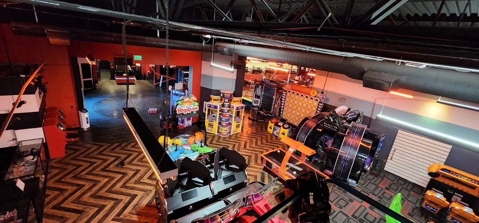 An arcade and entertainment area with racing simulators, arcade games, and playground equipment, featuring colorful lighting and a modern interior design.