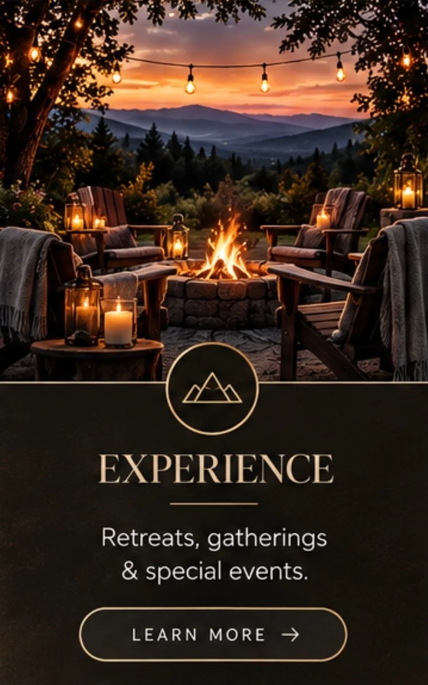 An outdoor evening scene with a fire pit surrounded by wooden chairs draped with blankets, illuminated by lanterns and candles, overlooking a mountain range at sunset with string lights hanging overhead.