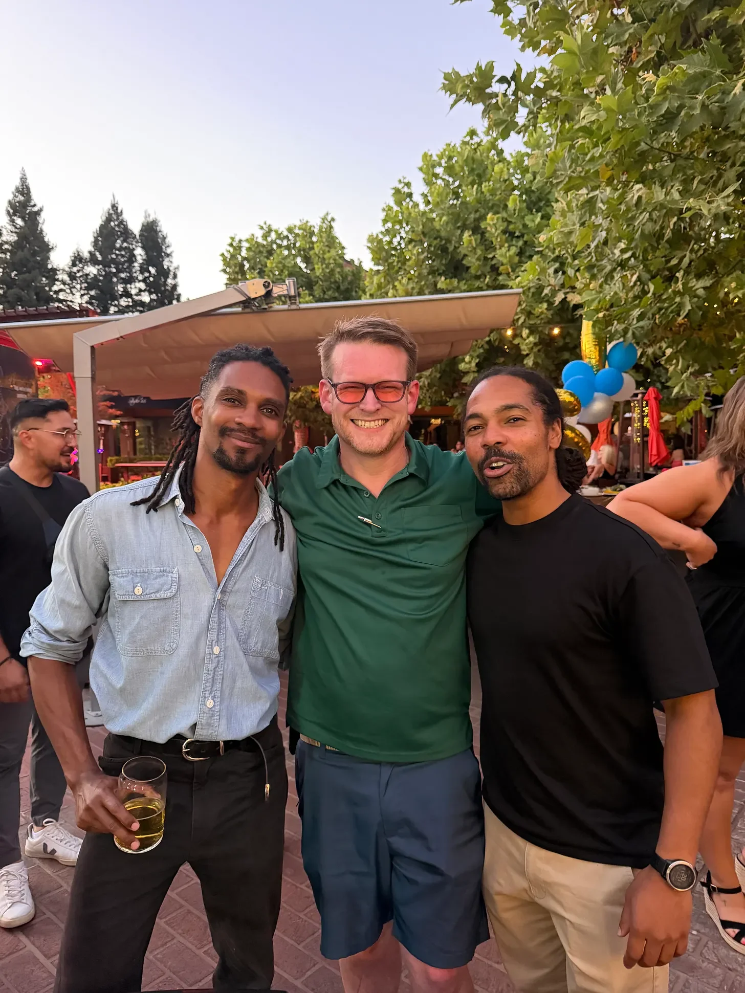 Three friends standing together outdoors at their high school reunion.