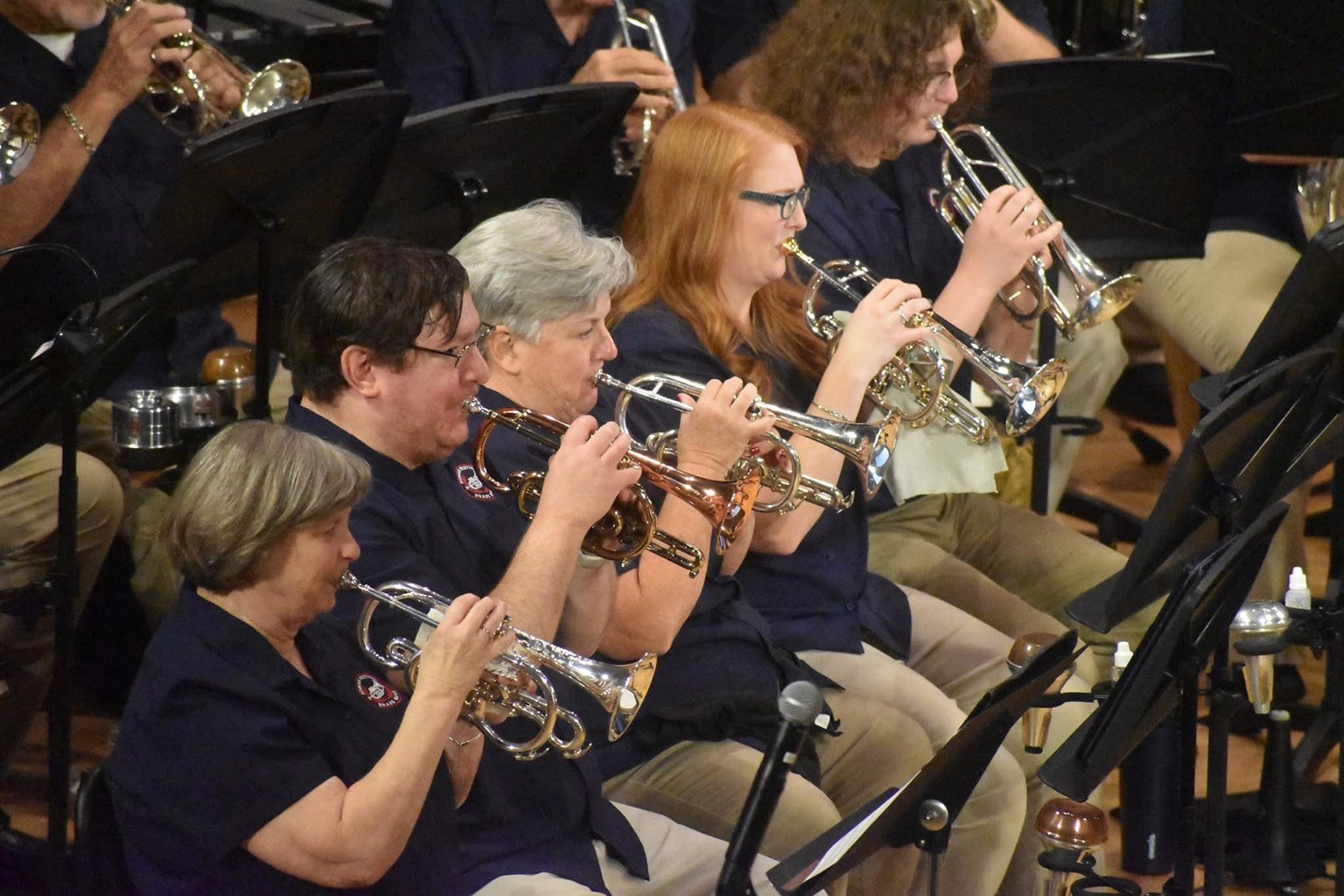 The first row cornet section of the Roman Festival Brass Band performing during a concert.