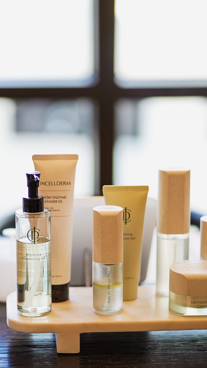 Skincare products on a wooden tray, including cleansing oil, foam cleanser, and moisturizer.