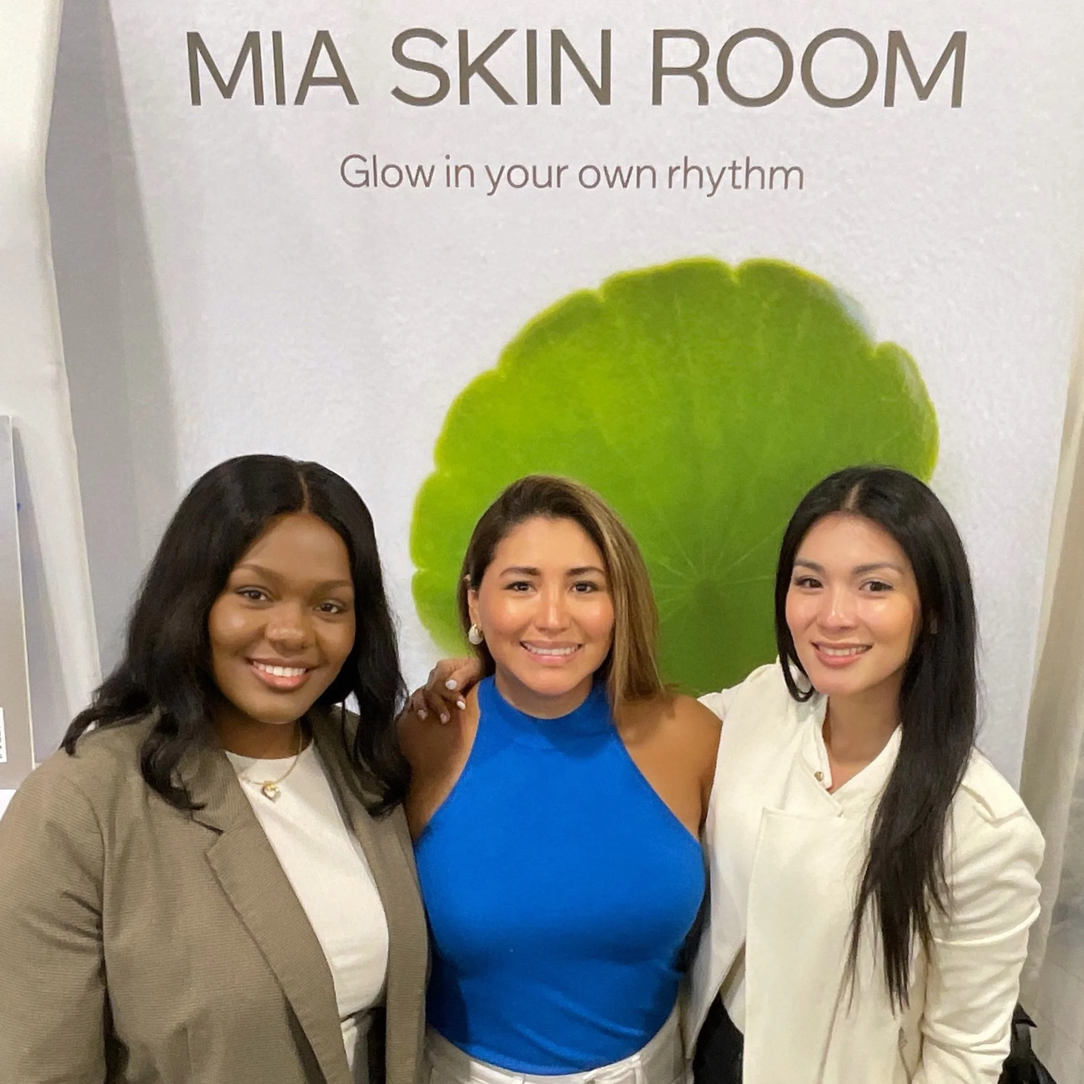 Group of women standing in front of a sign that says 'Mask Room' with a subtitle 'Glow in your own rhythm,' with a green decorative element above their heads.