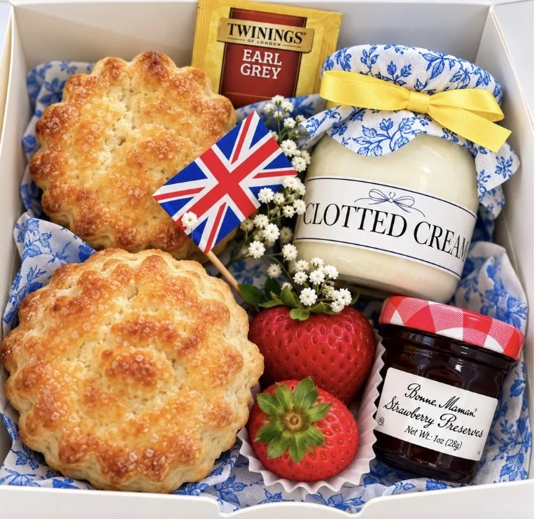 Orlando Scone Co. Cream Tea Box with two Queen scones, clotted cream, strawberry preserves, fresh strawberries and Earl Grey tea, tied with a blue floral cloth and yellow ribbon