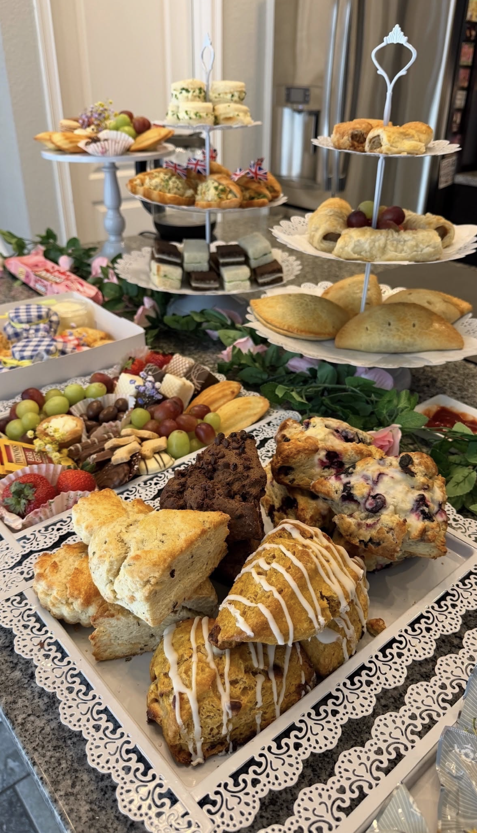 Assorted pastries, cakes, and finger foods arranged on a multi-tiered tray and serving platter for a dessert table.