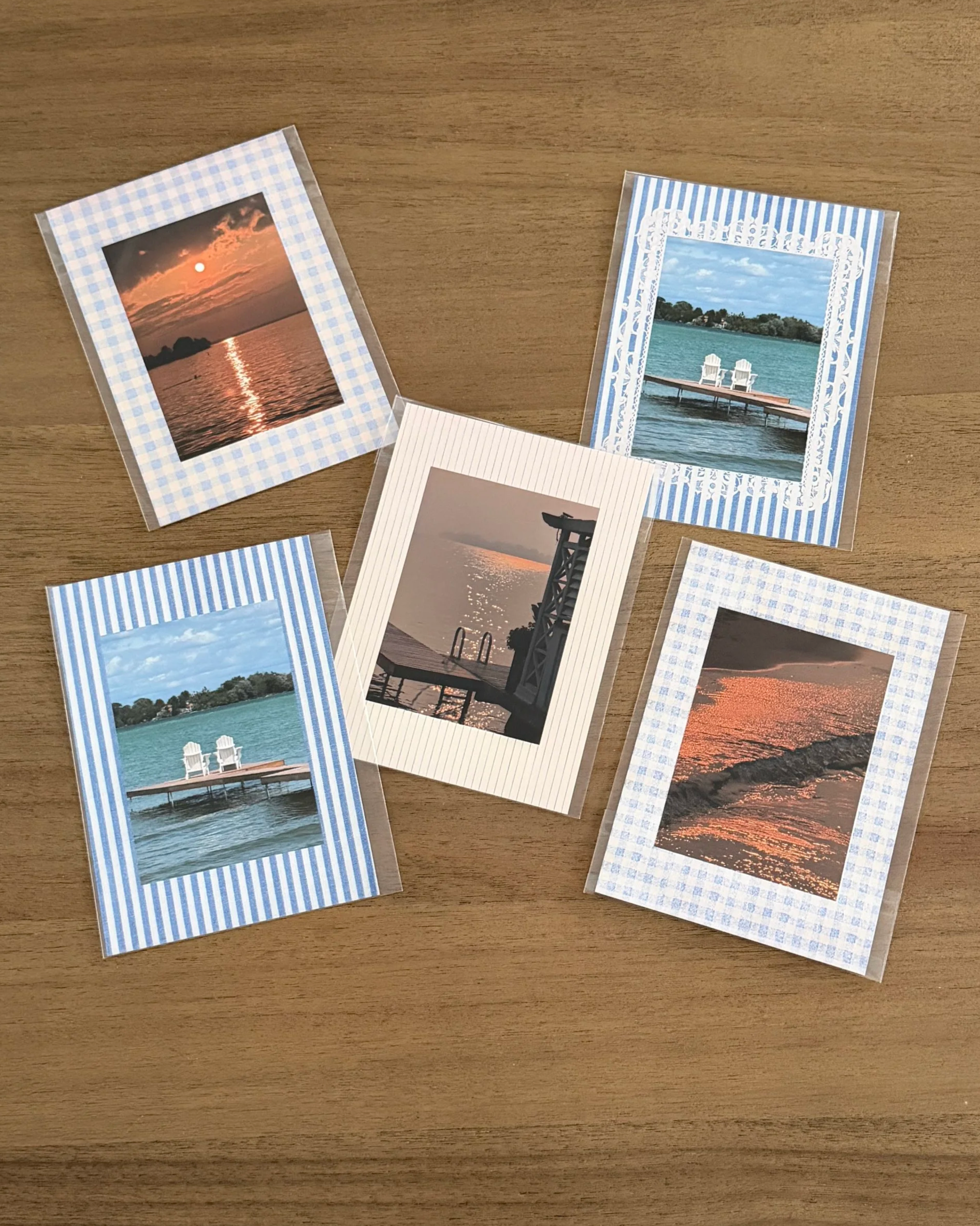 Collection of photographs on a wooden surface, featuring sunset and water scenes, some with striped borders and others with white borders.