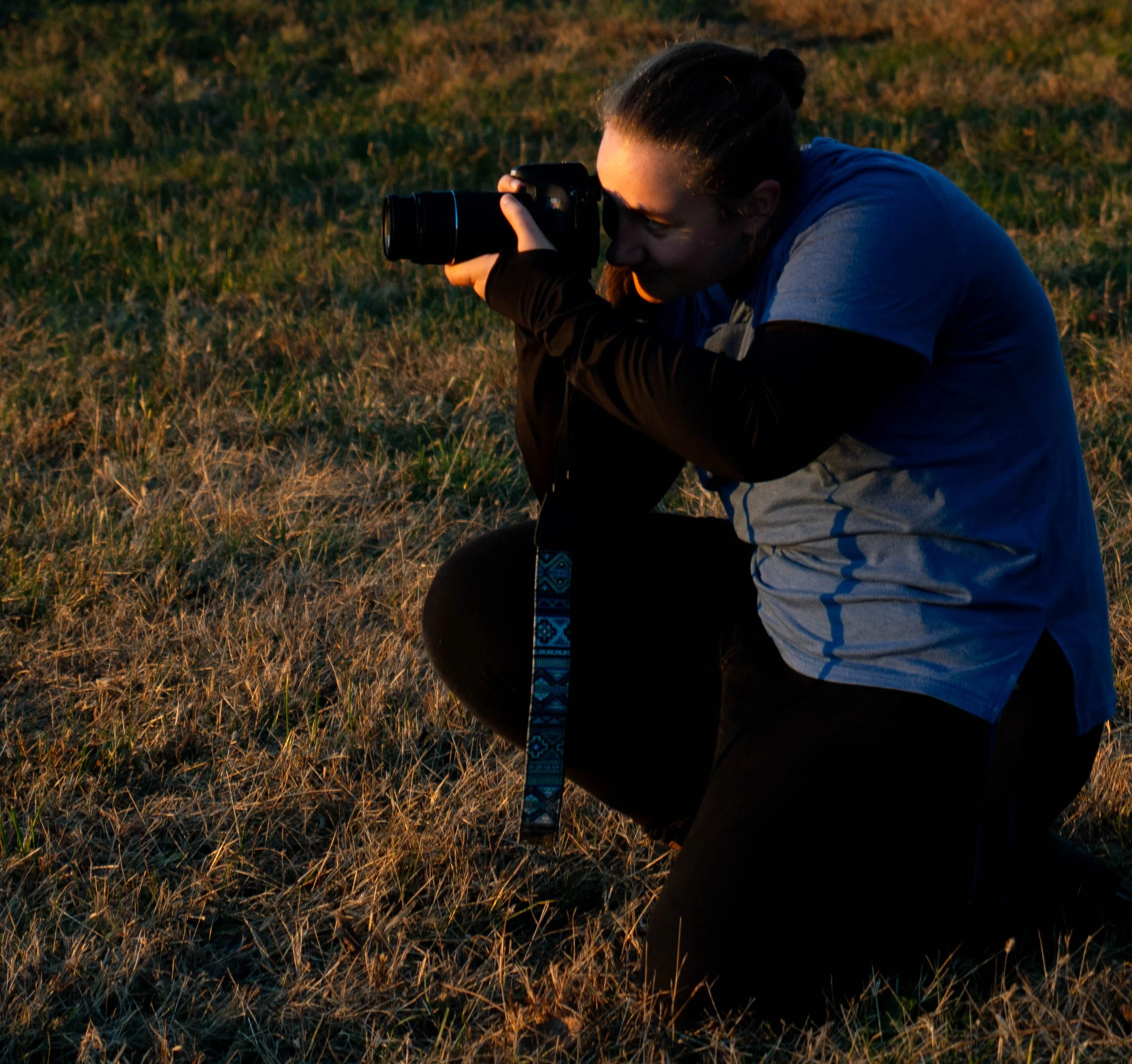 Parren photographing outdoors in a grassy field at golden hour.