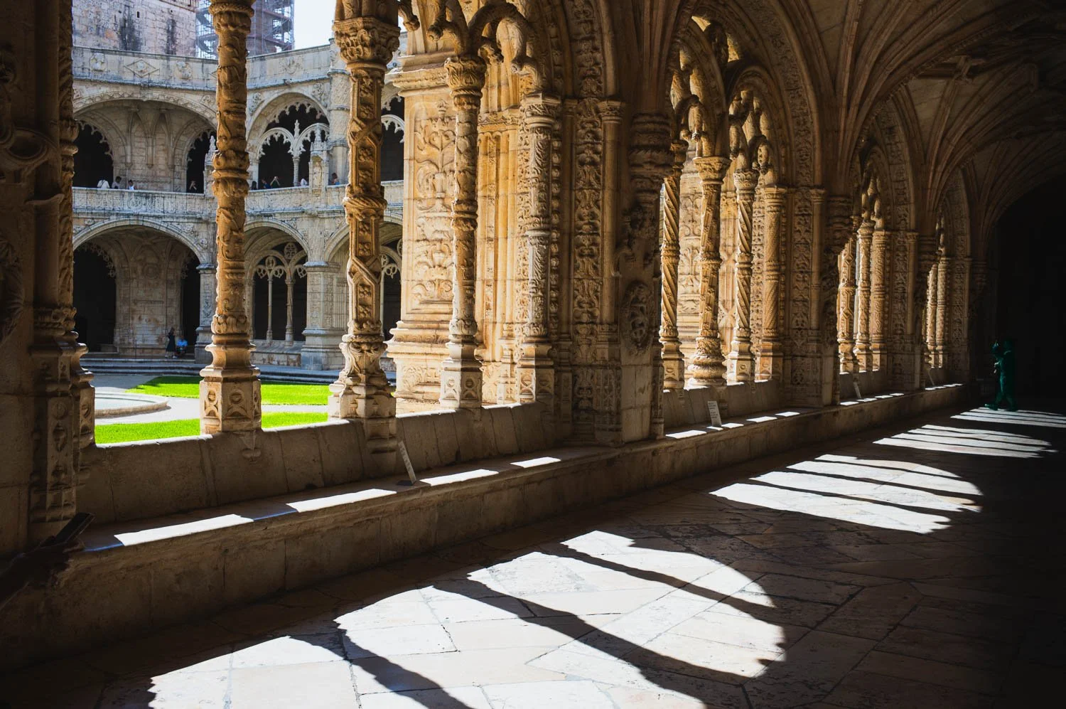 Sunlight and arch shadows across the stone floor of the Jerónimos Monastery cloister in Belém