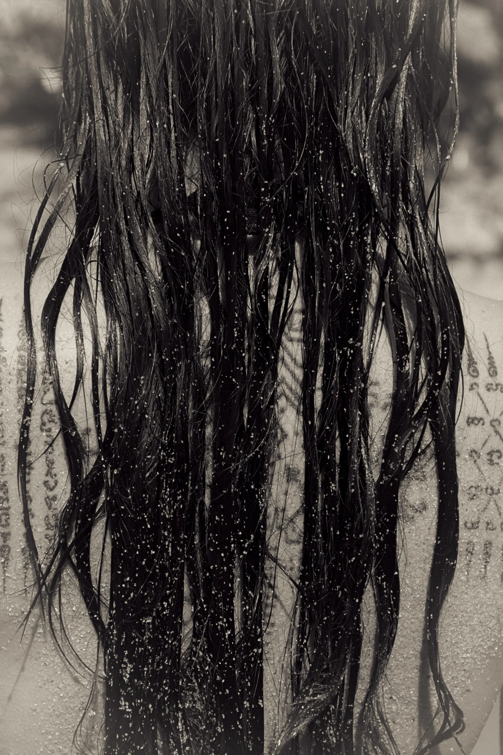 Wet hair dusted with sand over a tattooed back, 35mm film